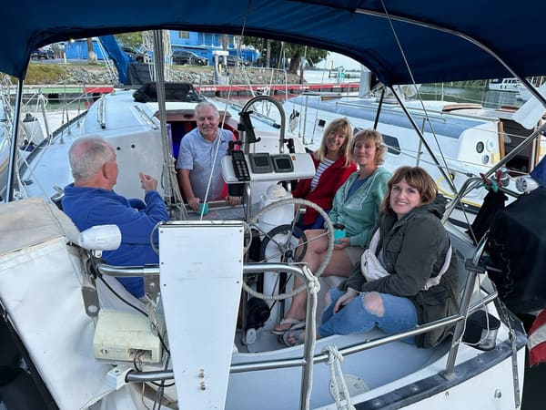 Yacht club members sitting in the cockpit of a sailboat while docked
